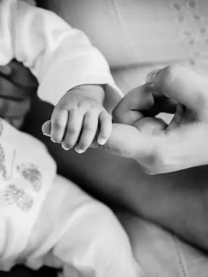 The tiny grip of a newborn's hand around their mother's finger. A close-up detail shot that speaks volumes.
