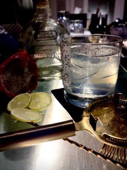 The Jelisco Dragon, one of our signature cocktails. This refreshing drink features tequila, dragon fruit seeds, and fresh lime, perfect for a summer evening.