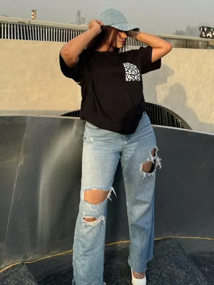 Adjusting the denim cap, a key accessory for this street style outfit.