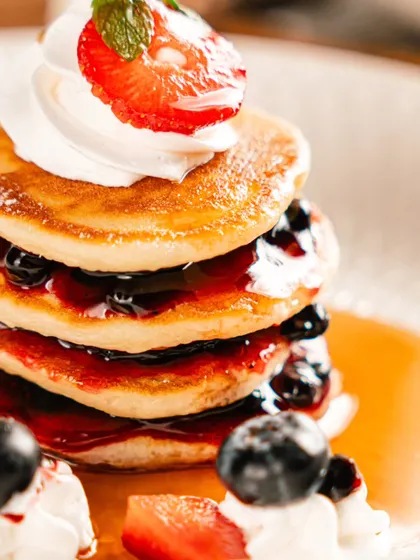 A close-up of a stack of pancakes at Amelia, but the focus on presentation makes it relevant to the overall beverage and dessert art.