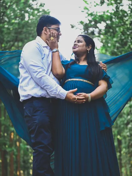 Using a flowing piece of fabric adds movement and a touch of elegance to this forest maternity photo, framing the couple beautifully.