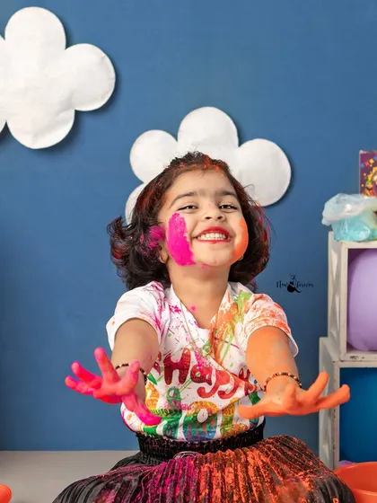A huge, colorful smile from a little girl enjoying our Holi mini session. Her face and hands are covered in safe, organic colors, showing the pure joy of the festival.