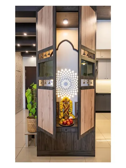 This exquisite puja unit is designed as a standalone piece of furniture. The wooden doors open to reveal a beautifully lit interior with a traditional arch and a backlit mandala design, creating a space where spirituality meets sophistication.