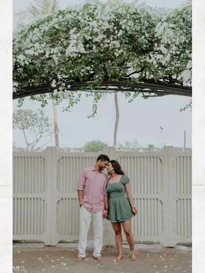 A beautiful wide shot of the couple under an arch of white flowers, creating a perfect frame.