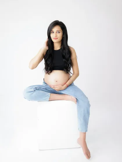A duplicate of image 83, this confident and modern portrait in a black crop top and jeans showcases the baby bump with style.