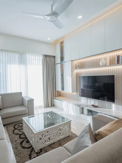 A spacious living room designed for comfort, featuring a large sectional sofa and a full-wall entertainment unit. The warm backlighting on the TV panel creates a cozy ambiance for evening relaxation.