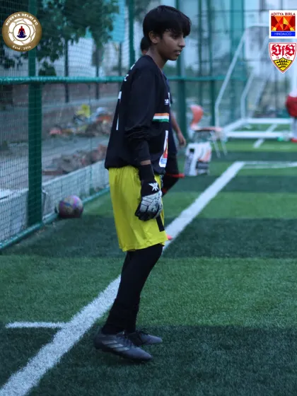A young goalkeeper stands ready during a drill at the VfB Stuttgart camp. We provide specialized training for every position on the field, ensuring holistic team development.