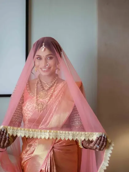 A playful moment with the veil. The bride smiles warmly, her personality shining through in this lovely portrait, with modern decor elements in the background.