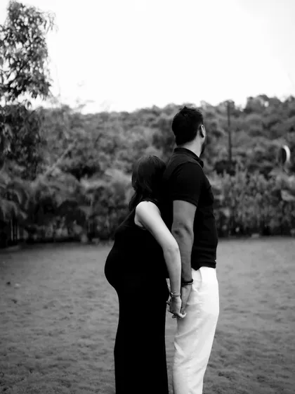 A black and white shot of the couple standing back-to-back while holding hands, looking out in opposite directions. It's an artistic pose symbolizing their unity and individual strength.