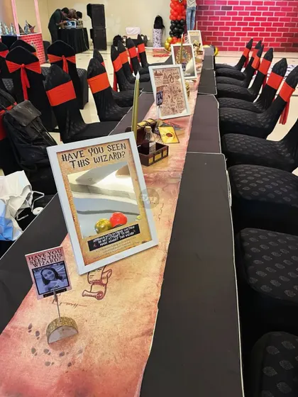 A closer look at the long table setup, with 'Have You Seen This Wizard?' mirror signs and other magical props.