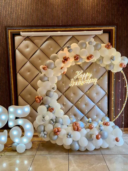 A different view of the elegant 25th anniversary decor. The soft lighting on the balloon arch and marquee numbers creates a warm and celebratory atmosphere, highlighting the milestone in a sophisticated way.