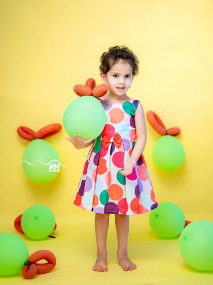 A colorful summer fruit themed birthday shoot. The bright colors and fun balloon apples make for a cheerful and vibrant portrait.