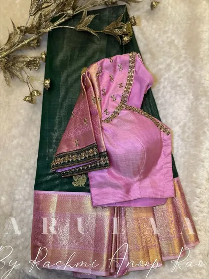 A beautiful pink blouse paired with a dark green Kanjivaram saree. The blouse features minimal buti work, allowing the rich colors of the outfit to stand out.