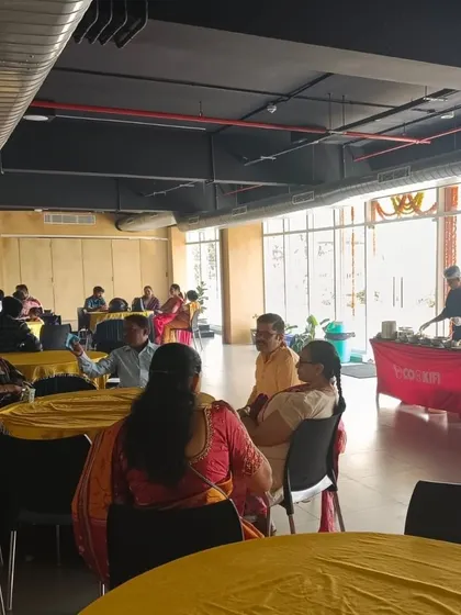 A wide view of a party in a clubhouse, with guests seated at tables and our catering station actively serving.
