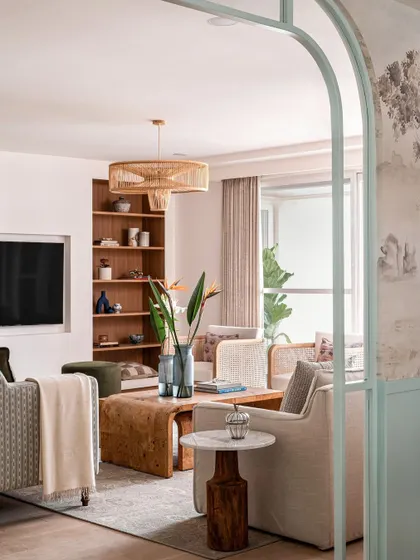 The crisp tones of blues and greens in the living room are balanced by the warmth of wood. A built-in bookshelf in a rich wood tone provides a beautiful backdrop for styling and display.