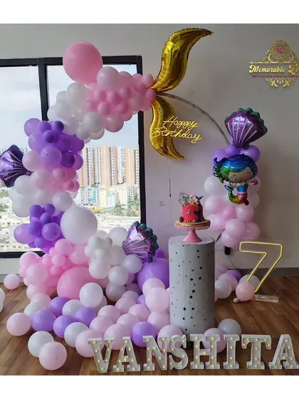 Another mermaid-themed setup for a 7th birthday, featuring a mix of pink and purple balloons and mermaid tail foil balloons.