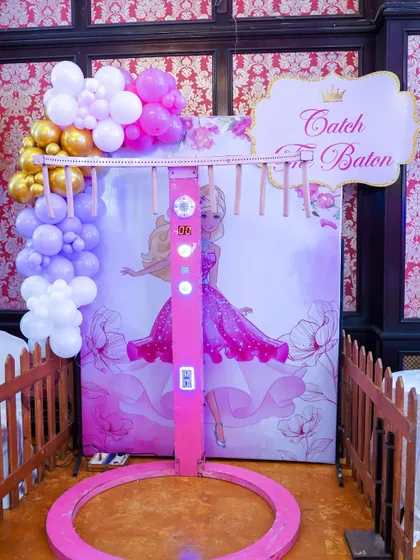 The 'Catch The Baton' game, a test of reflexes where players try to grab falling batons. This one is themed for a Barbie party.
