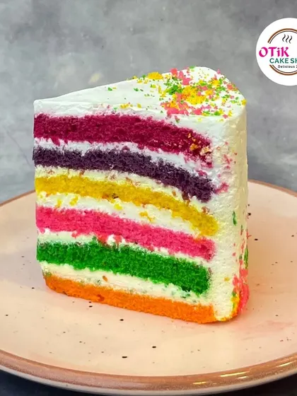A slice of our vibrant Rainbow Pastry. With its colorful layers and light, creamy frosting, it's a feast for the eyes and the palate, perfect for brightening up your day.