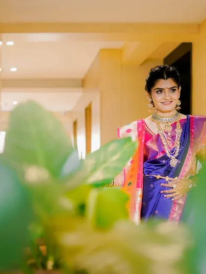 A lovely portrait of a Marathi bride, framed by green leaves. Her traditional attire and gentle smile are the focus of this beautiful, natural shot.