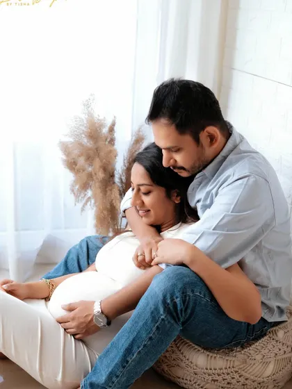 A relaxed and intimate moment. This casual pose on a pouf by the window creates a beautiful, lifestyle feel for a couple's maternity portrait.