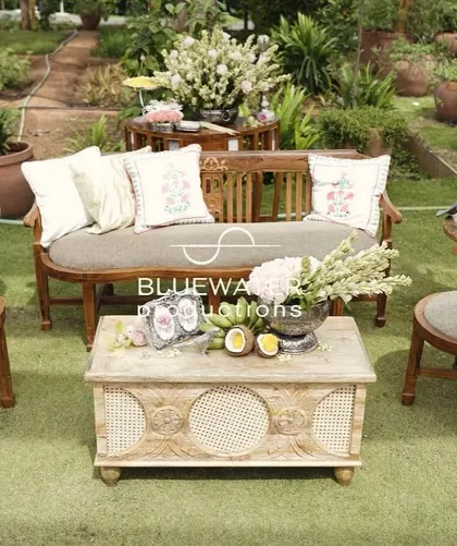 An elegant and fresh Haldi setup with rustic wooden furniture, white florals, and a relaxed garden party feel.