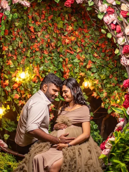 An intimate moment inside the floral nest prop, surrounded by lush greenery and warm lights. A perfect little world for the parents-to-be.