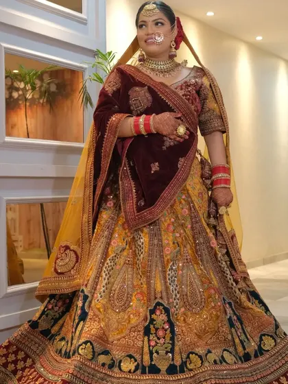 A full-length view of a bride in my multi-colored rental lehenga with a velvet dupatta. The look is accessorized with a gold-plated choker set, showcasing a complete and ready-to-wear bridal option.