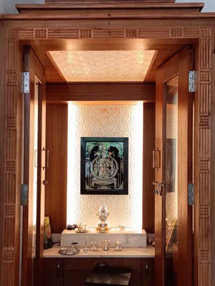 This classic pooja room design features intricately carved wooden doors and a beautifully lit interior. The use of glass panels with traditional motifs allows for a sense of openness while maintaining the sanctity of the space.
