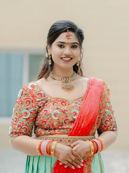 A portrait of a smiling bride in a colorful lehenga, ready for one of her wedding functions. The bright colors reflect the festive atmosphere.