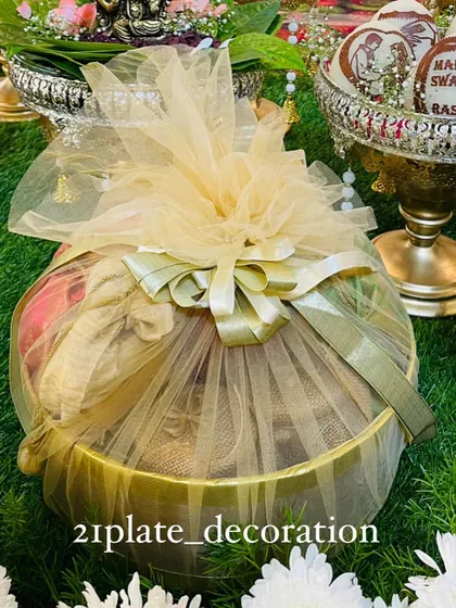A beautifully wrapped gift basket, perfect for presenting seer plates or return gifts. The elegant net wrapping and bow add a touch of class to the traditional offerings.