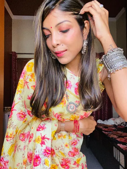 A closer look at the styling of the floral saree, showing the silver jhumkas and bangles that add a traditional touch to the modern printed fabric.