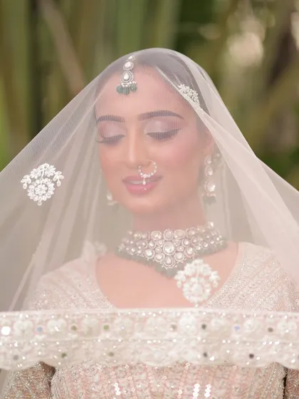 A dreamy shot through the veil. The soft-focus effect highlights the delicate eye makeup and the bride's serene expression.