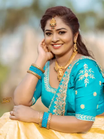 A happy client looking radiant in a traditional yellow and turquoise lehenga set. The gold jewelry and embroidered blouse complete this festive look.
