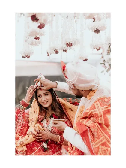 The Sindoor Daan, a pivotal moment in a Hindu wedding. The groom applies sindoor to his bride's hair parting, symbolizing their union. I capture this with a focus on the tenderness and significance of the gesture.