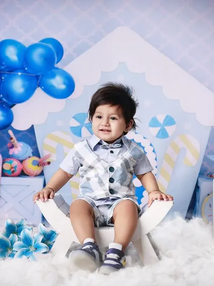This little boy is all smiles in our blue candy-themed first birthday setup. The detailed backdrop and props create a complete and immersive scene for his special photos.