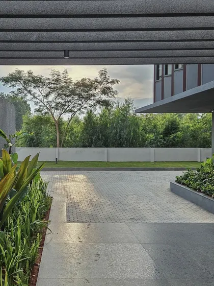 The view from the covered entrance walkway, looking out onto the landscaped grounds. The pergola structure frames the view, creating a deliberate and peaceful transition from the exterior to the interior.