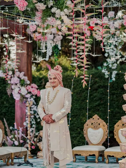 The groom stands at the mandap, ready to welcome his bride. The decor, with its pink and gold tones, was designed to feel both grand and romantic.
