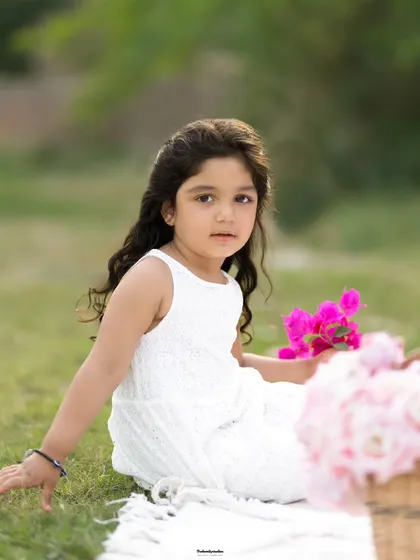 A peaceful moment as a young girl sits on a blanket in the grass during her outdoor photoshoot.