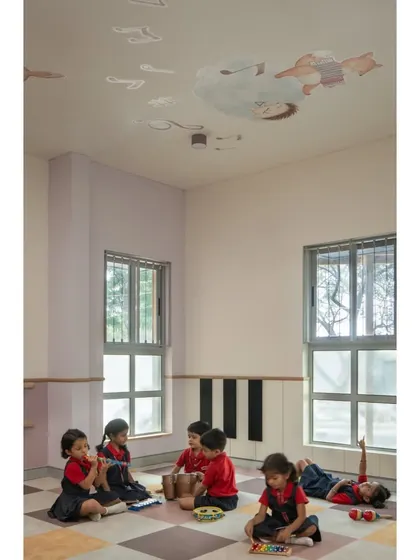 A music and movement room where children can express themselves freely. The ceiling is decorated with musical notes and figures, and the open floor plan allows for dance, play, and learning with instruments.