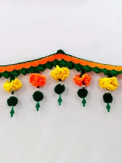 This is one of my best-selling toran designs, featuring hanging tassels made of crochet flowers and pom-poms. The scalloped shape adds a beautiful decorative arch to any doorway.