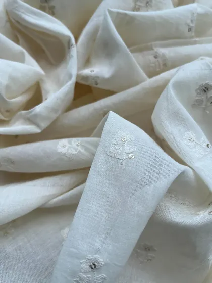 A beautiful off-white embroidered cotton with delicate floral butis and sequin highlights, showcasing its natural beauty and timeless appeal.