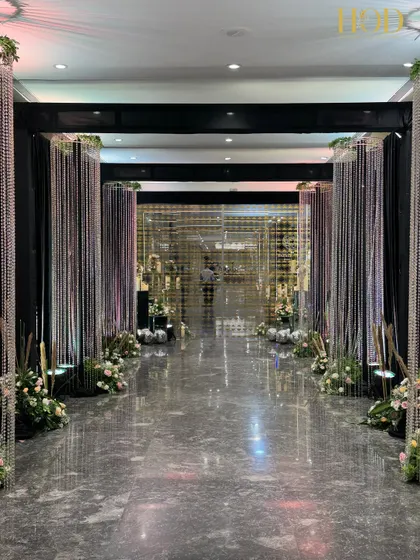 This modern and glamorous hallway features columns of sparkling crystal strings and a reflective floor. The design creates a dazzling tunnel of light, perfect for a chic wedding reception or cocktail party entrance.