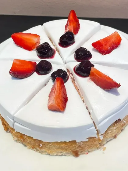 A full view of our Milk Pastry cake, pre-sliced and topped with fresh strawberries and blueberries. Perfect for parties and events.