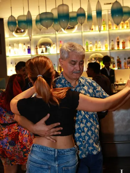 A couple in a close embrace, dancing near the bar. The warm lighting and social setting create a perfect backdrop for a night of dancing.