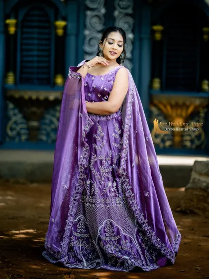 A close-up of the purple cape lehenga, showing the detailed silver embroidery on the blouse and skirt.