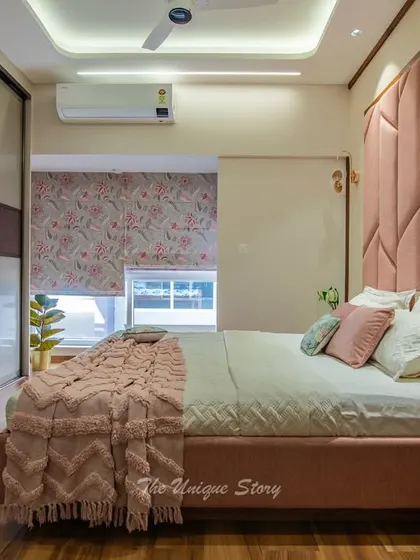 A beautifully transformed daughter's bedroom in shades of pink. The room features a dramatic, geometrically upholstered headboard, a cozy pink bed, and sleek sliding wardrobes with a lacquered glass finish.