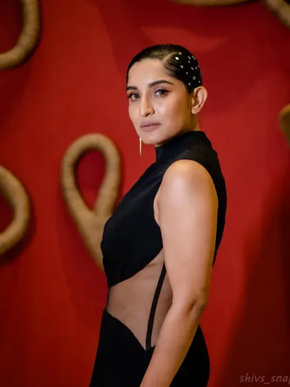 A side view of the black mermaid gown, showing the daring sheer panel that cuts across the waist and back. The high neckline adds a touch of sleek sophistication to balance the look.