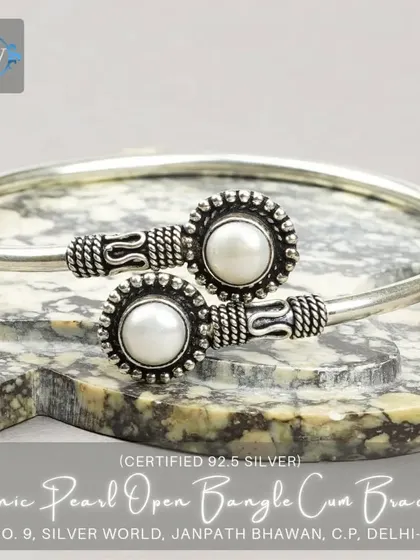 An ethnic open bangle featuring two original mother-of-pearl studs in a granulated silver setting. A beautiful blend of classic and traditional design.