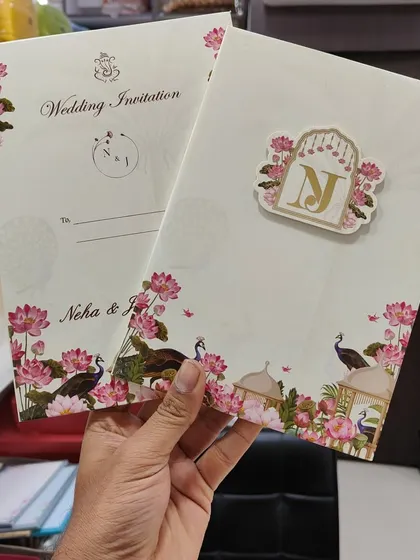 This full view shows a Pichwai wedding invitation with peacock and lotus motifs, complete with a matching insert and a custom gold initial tag.