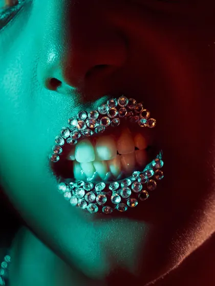A creative beauty editorial focused on lip styling. We used carefully placed crystals on the lips and dramatic lighting to create a unique, high-fashion, and slightly edgy macro shot.